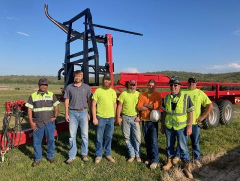 Team of men in jeans and casual PPE pose with a bailer